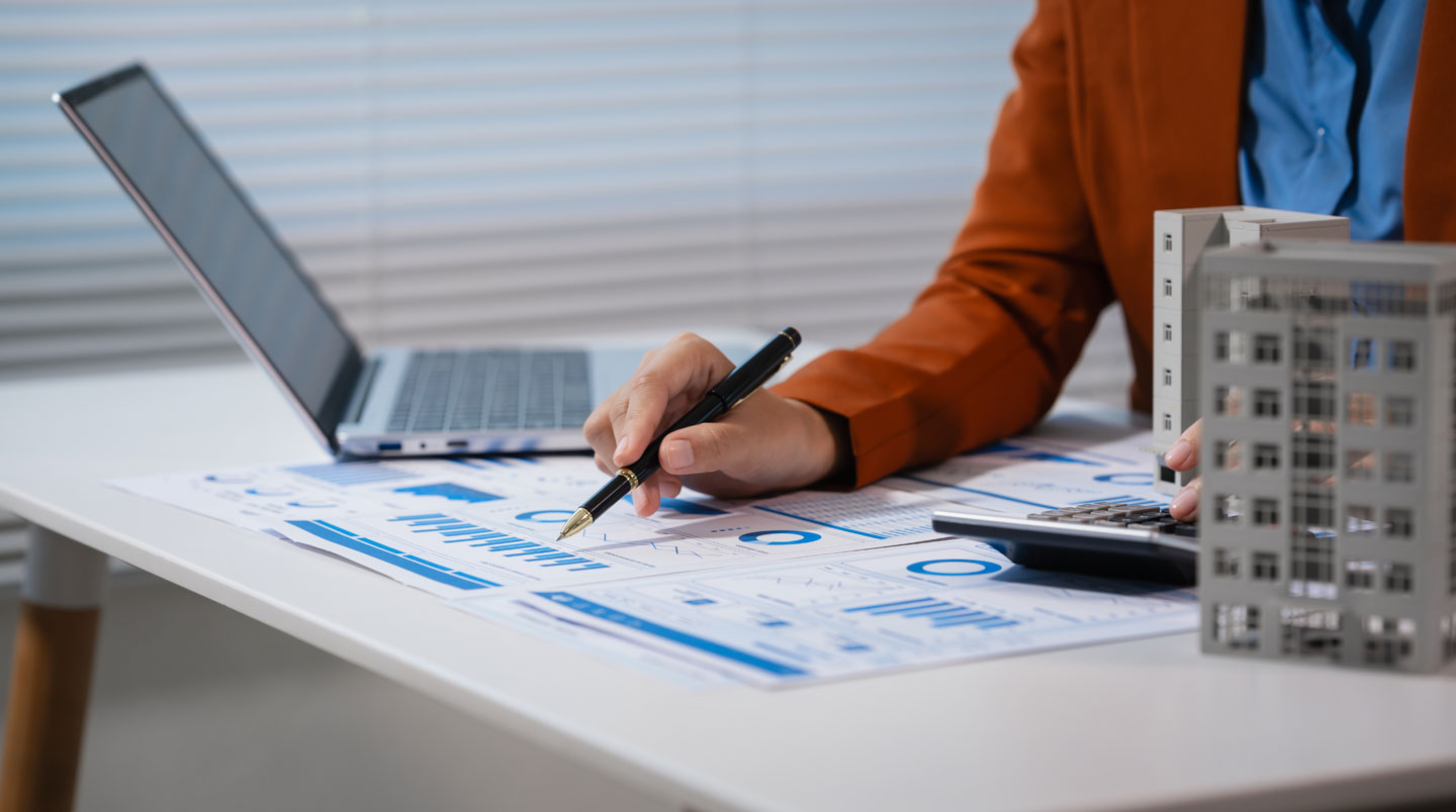 Bureau de conseiller patrimonial avec documents de calcul de rentabilité immobilière et tableur financier sur écran